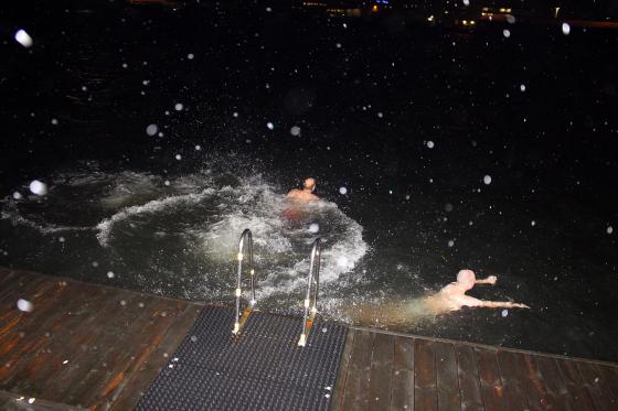 Bilde av tre gutter/menn som hopper ut i vannet. Det er regndr&aring;per i bildet, som viser at det regner, samtidig som der er m&oslash;rkt