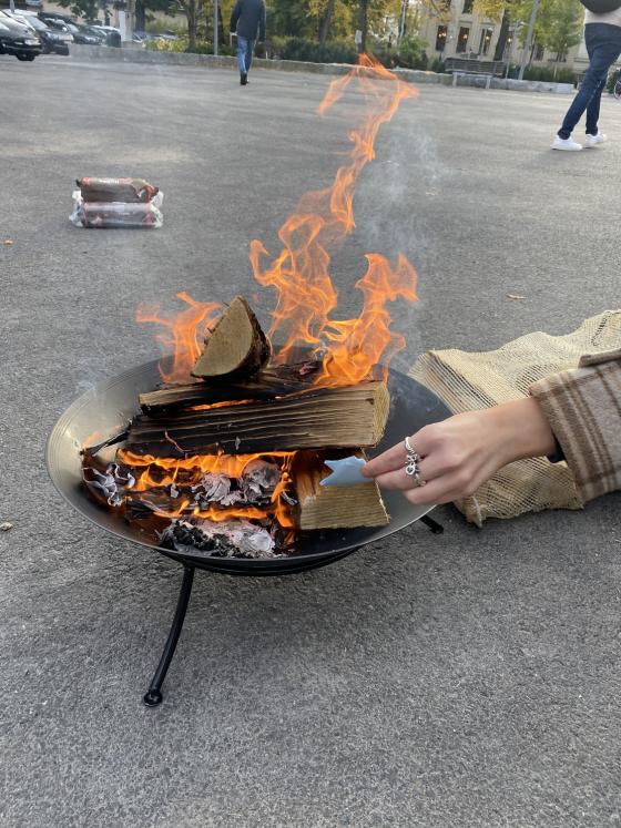 Bilde av et b&aring;l som brenner, med en h&aring;nd som stikker en lapp inn i b&aring;let.