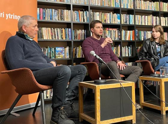 Tre mennesker sittende p&aring; en scene