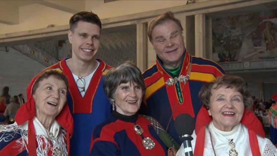 Fem samer som st&aring;r og smiler 