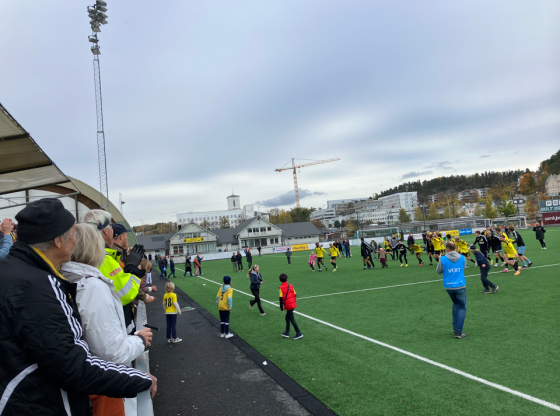 Bilde fra Sandvika Stadion. B&aelig;rum sine alagsspillere er stilt opp p&aring; rekke, holder hverandre i hendene, og er p&aring; vei til &aring; gj&oslash;re den s&aring;kalte b&oslash;lgen overfor gjenv&aelig;rende fans p&aring; tribunen etter kampen mot Tr&aelig;ff.