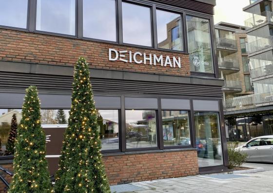 P&aring; utsiden av Deichman R&oslash;a. To tr&aelig;r med lys foran bygningen.