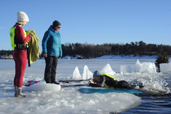 En elev ligger i vannet, mens en l&aelig;rer f&oslash;lger med.