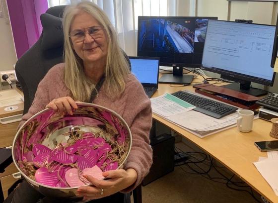 Eldre dame holder et s&oslash;lvfat med lilla hjerter oppi