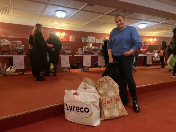 Dame som st&aring;r p&aring; Hotel Christiania Teater med julegaver til God jul, lille venn