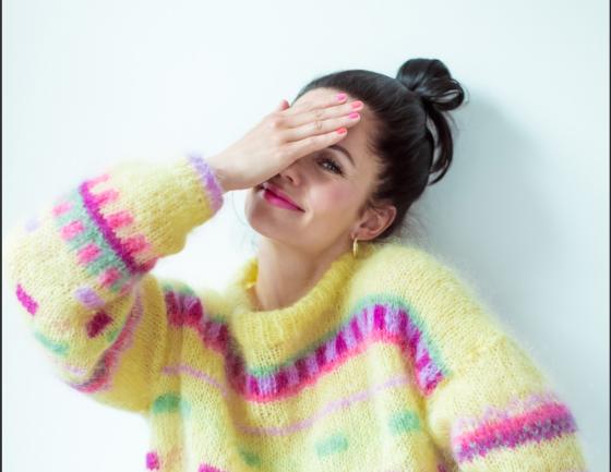 Bildet viser jurist Julie Embr&aring; i egendesignet genser Fizzy Pop. Genseren er gul med fargerikt m&oslash;nster.