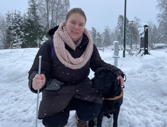 Bildet viser en jente som sitter b&oslash;yd ned ved siden av hunden sin. Hunden er svart. 