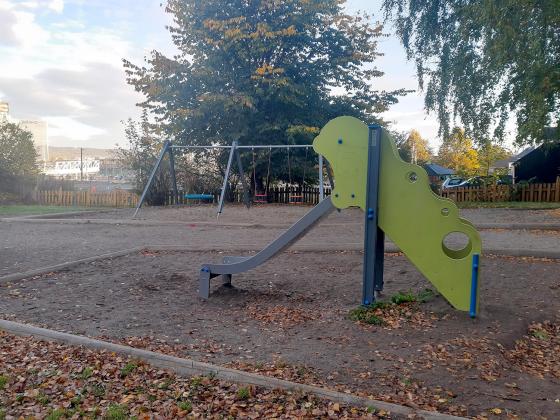 Lekeplassen til Gamlebyen barnehage. Bilde viser en sklie og to husker i bakgrunnen.