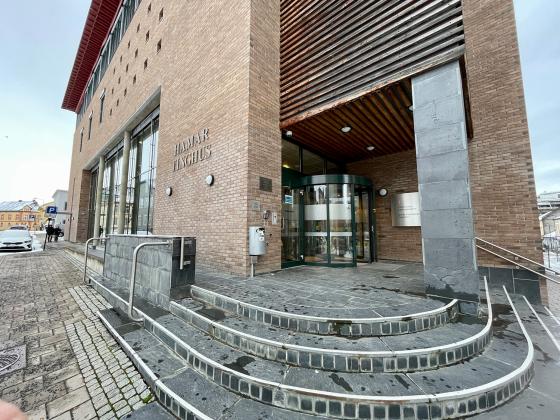 Foto at et stort steinhus, med en tilh&oslash;rende steintrapp. Hamar Tinghus har skifertrapp og er bygget i murstein. Det har store glassvinduer. 