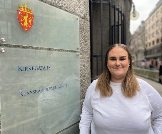 Kvinne st&aring;r foran Kunnskapsdepartementet