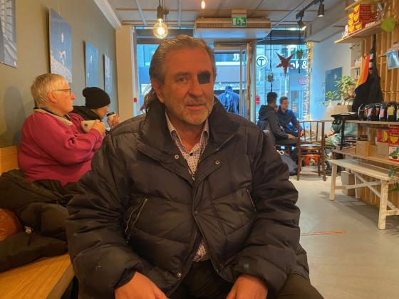 En mann med en &oslash;yelapp ser inn i kameraet