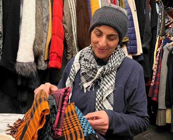 dame foran vegg av kl&aelig;r, ser igjennom skjerf