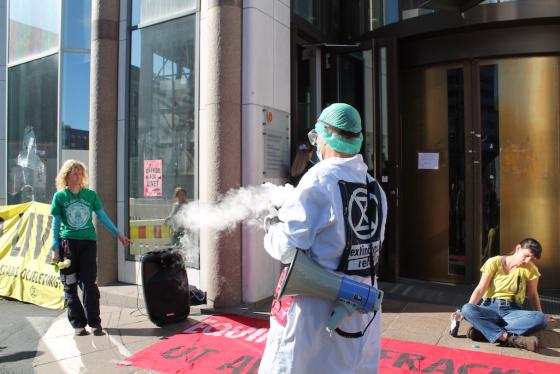 En dramatisk oppsetning blir gjennomf&oslash;rt utenfor departementet. En mann p&aring;f&oslash;rt en drakt holder en krukke med noe som skal illustrere olje. 