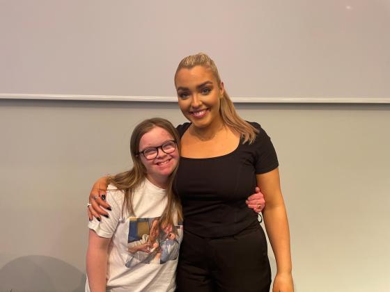 Angelika Fjellvang Lie og Selene Fjellvang Lie smiler p&aring; scenen ved siden av hverandre etter de har holdt foredraget