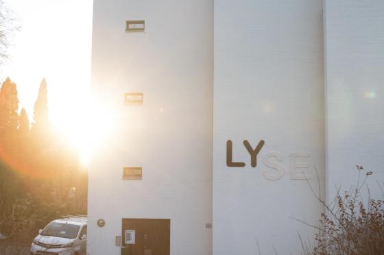 Ordene LY og SE blir satt sammen til ordet LYSE p&aring; kirkeveggen til Sinsen kirke. Det er lav sol i bakgrunnen.