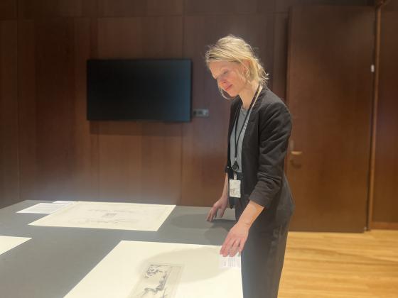 Bilde av kvinne som kikker p&aring; bilder p&aring; et bord p&aring; Nasjonalmuseet