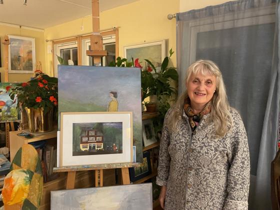 Gerd Eva Baum-Thoresen st&aring;r foran sitt egetmalt maleri av Kobro-huset.