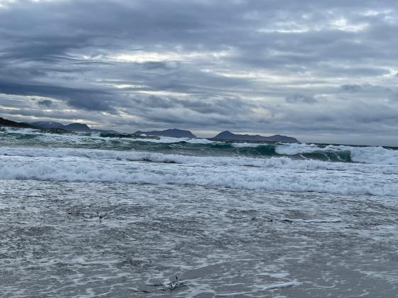Hav med mange b&oslash;lger, og fjell i bakgrunnen