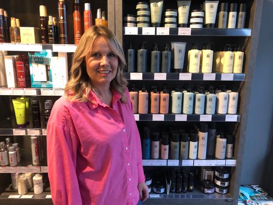 Bilde av fris&oslash;r foran en hylle med produkter