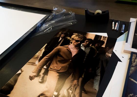 Man ser et bord, med bilderammer og bilder p&aring;, med teip og tusjer str&oslash;dd rundt p&aring; bordet. 