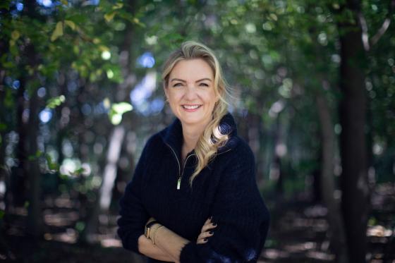 dame med blondt h&aring;r smiler mot kamera 