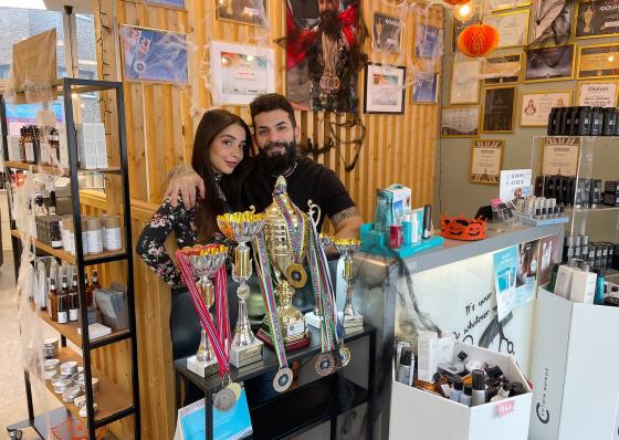 Nashwa Shosho og Karam Abdelhadi st&aring;r foran flere av seierspokalene til fris&oslash;rsalongen. 