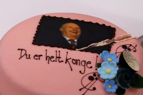 En rosa kake med bilde av kong Harald p&aring;. Teksten under st&aring;r det "Du er helt konge"