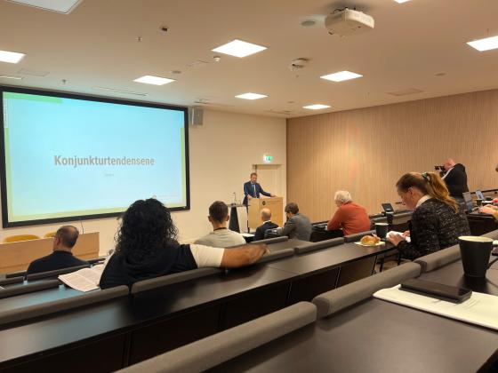 En sal med noen mennesker, projektor og en p&aring; talerstolen