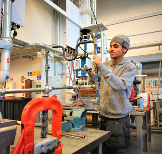 En av elevene p&aring; bygg og anlegg skrur p&aring; r&oslash;r.