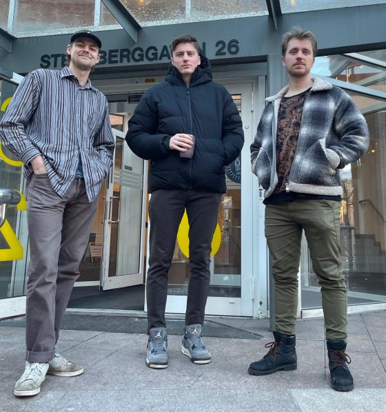 Tre unge menn st&aring;r foran inngangen til en bygning p&aring; Oslomet