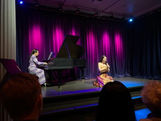 Operasanger sitter p&aring; scenen og pianist spiller piano