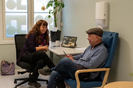 Digital l&aelig;rer sitter og hjelper eldre person med mobilbruk 