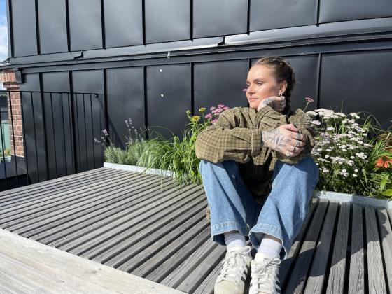 En dame, Mathea Monclaire, sitter p&aring; en benk i sola