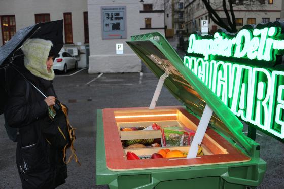 Kvinne som ser p&aring; s&oslash;ppeldunk med spiselig mat i. 