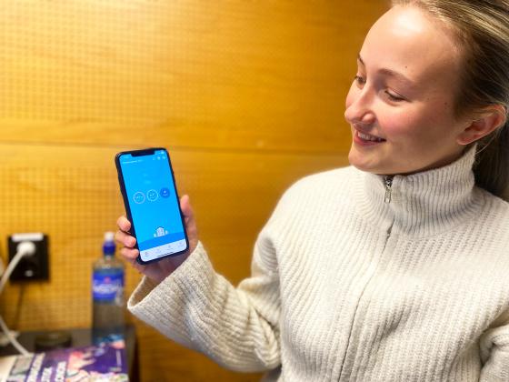 Student viser frem telefon med str&oslash;mapp