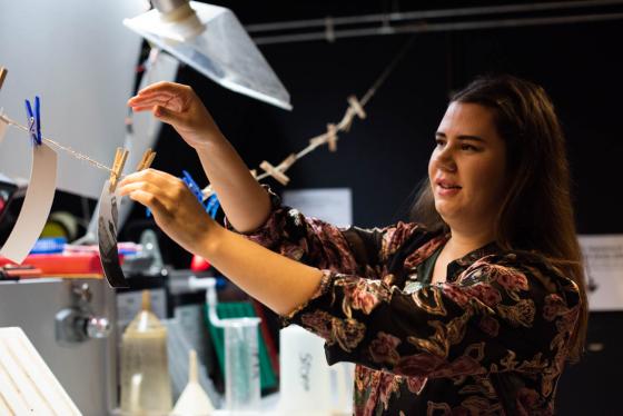 Hanne henger opp bilder p&aring; m&oslash;rkerommet.