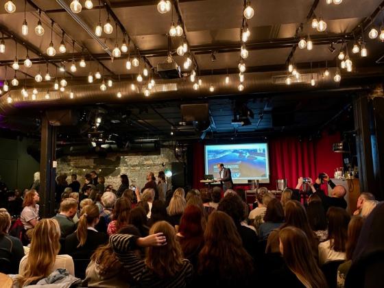 Publikum sitter vendt mot scenen hvor klima- og milj&oslash;minister Espen Barth Eide snakker p&aring; scenen. Noen av publikum st&aring;r med ryggen mot som en slags protest.