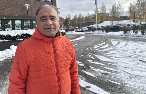 Ombir Singh Upadhyay st&aring;r i en oransje jakke utenfor et bygg p&aring; Stovner i Oslo. 