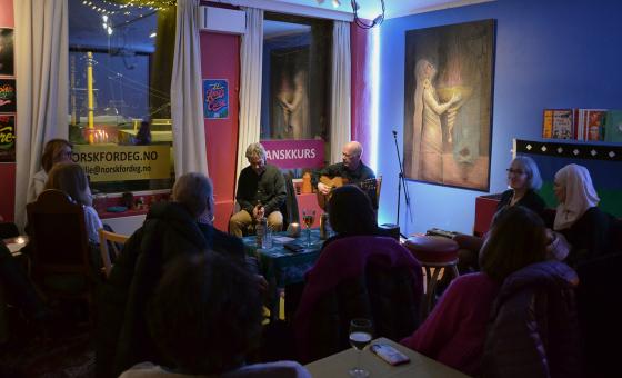 to sitter og spiller og synger flamenco. Du ser publikum bakfra,