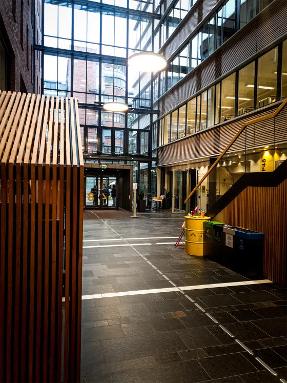 Bildet viser hovedinngangen av et skole bygg p&aring; Oslomet. Det er et &aring;pent inne omr&aring;de med mange glassvinduer som strekker seg flere etasjer opp, og flere klasserom