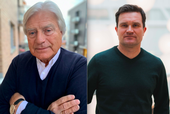 To menn ser inn i kamera, den ene med armene i kors, den andre med hendene p&aring; hoftefestet. 