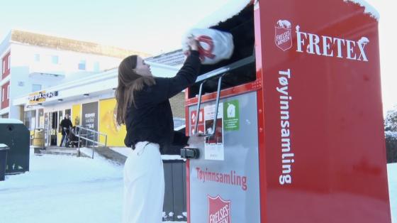 Jente kaster kl&aelig;r i Fretexboks. 