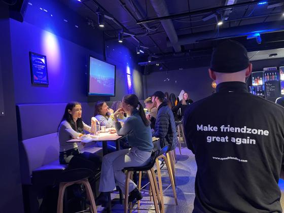 Victor Sanden (35) st&aring;r foran bord med speed friending deltakere. Han har slagordet "Make friendzone great again" bak p&aring; genseren. 