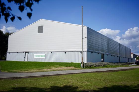 Den gr&aring; plasthallen T&oslash;yen Arena i solskinn