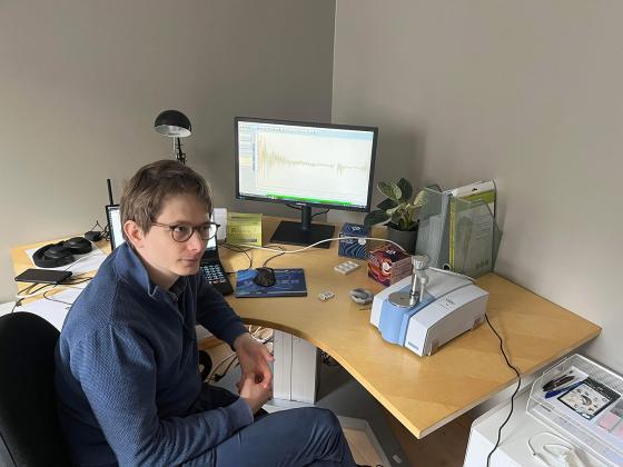 J&oslash;rn Kl&oslash;vfjell Mjelva sitter ved pulten sin, der han analyserer rusmidler med en test-maskin, og to pc-skjermer. 