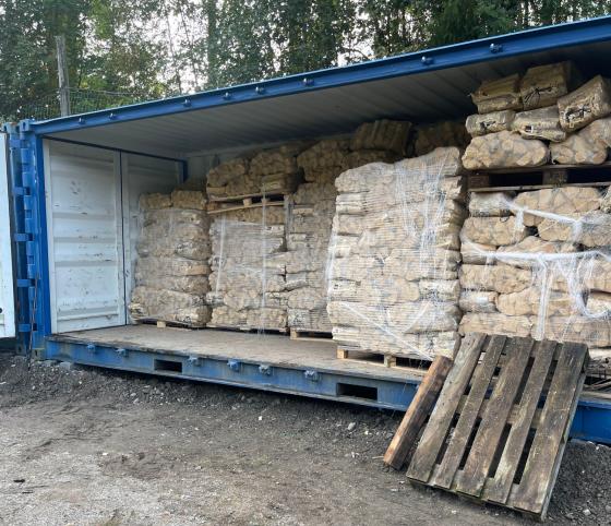 Bl&aring; container fylt med sekker med fyringsved