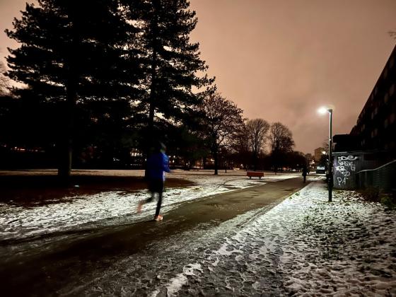 Det er m&oslash;rkt ute og mann jogger forbi p&aring; en vei med sn&oslash;