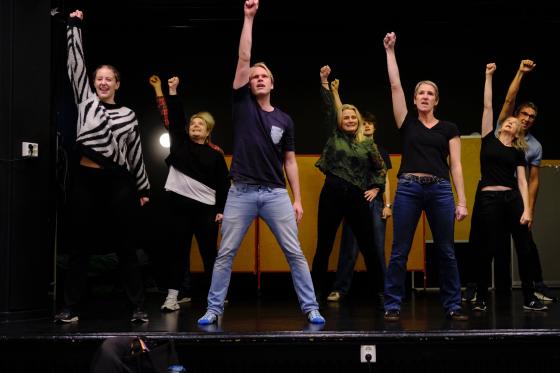 NI personer st&aring;r med en h&aring;nd i v&aelig;ret oppe p&aring; en scene