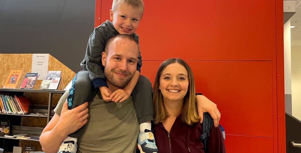 S&oslash;nnen sitter p&aring; faren sin rygg mens han holder rundt kona. Alle smiler.