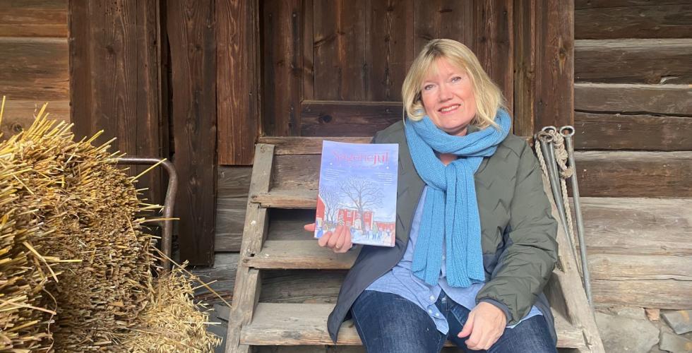 Dame som sitter p&aring; en trapp, hun holder et magasin som heter Sagenejul. Bildet er tatt p&aring; V&oslash;ienvolden g&aring;rd. 